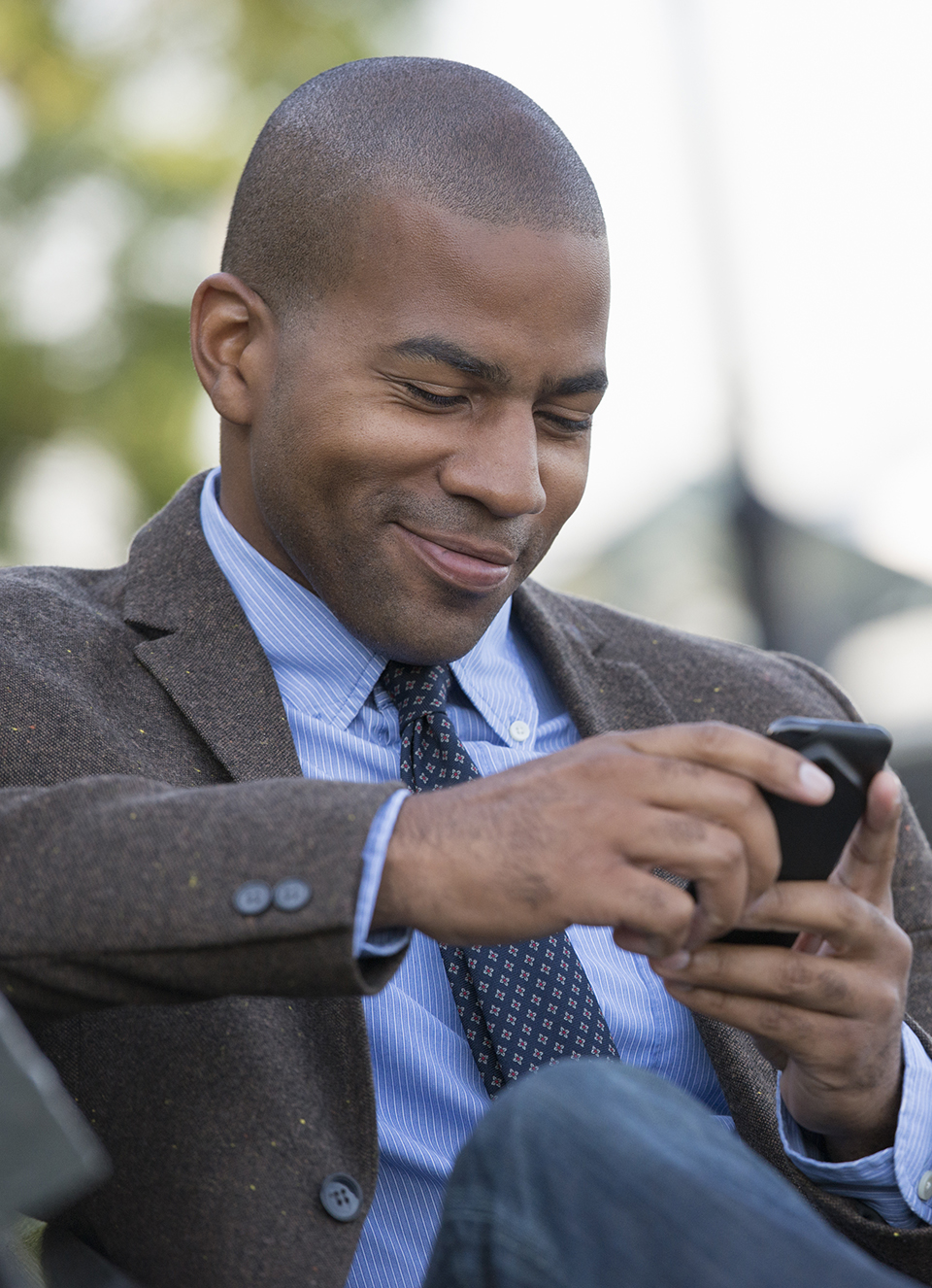 Urban Lifestyle,USA,Business people in the city. Keeping in touch on the move. A man seated using his smart phone. A man in the background.